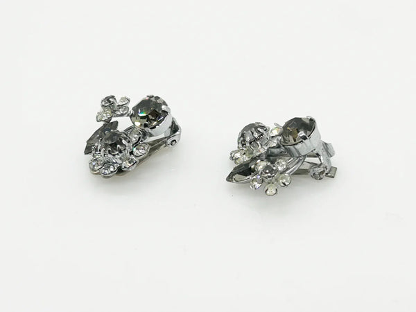 These vintage Sparkling Gray Austria Rhinestone Earrings captivate with their dazzling brilliance. Featuring a mix of gray and clear rhinestones expertly cut in marquise and round shapes, their intricate arrangement forms an elegant, eye-catching pattern