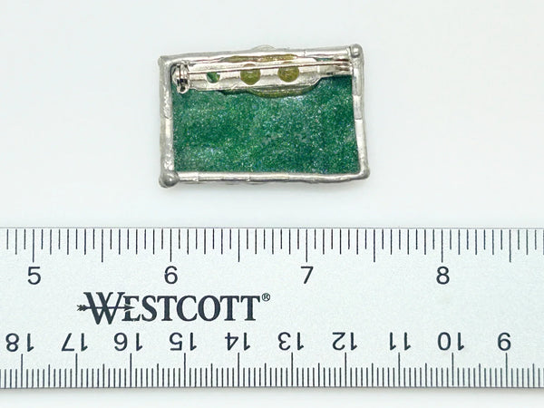 This charming stained glass pin celebrates individuality with a puzzle piece design crafted using authentic Tiffany-style copper foil work. Vibrant green and blue glass pieces are carefully soldered together to create a wearable conversation starter that doubles as meaningful advocacy.