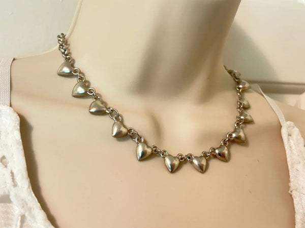 This charming necklace features heart shapes with sparkling round rhinestones at the center. Flip it over to reveal solid hearts with a sleek brushed finish—wear it whichever way suits your mood! Measuring 16" long, it’s secured with an adjustable whimsical flower clasp and a trusty lobster closure for a fun, flirty touch.