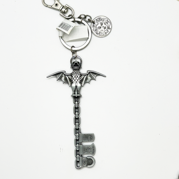 Silver key-shaped keychain with bat design on a white background