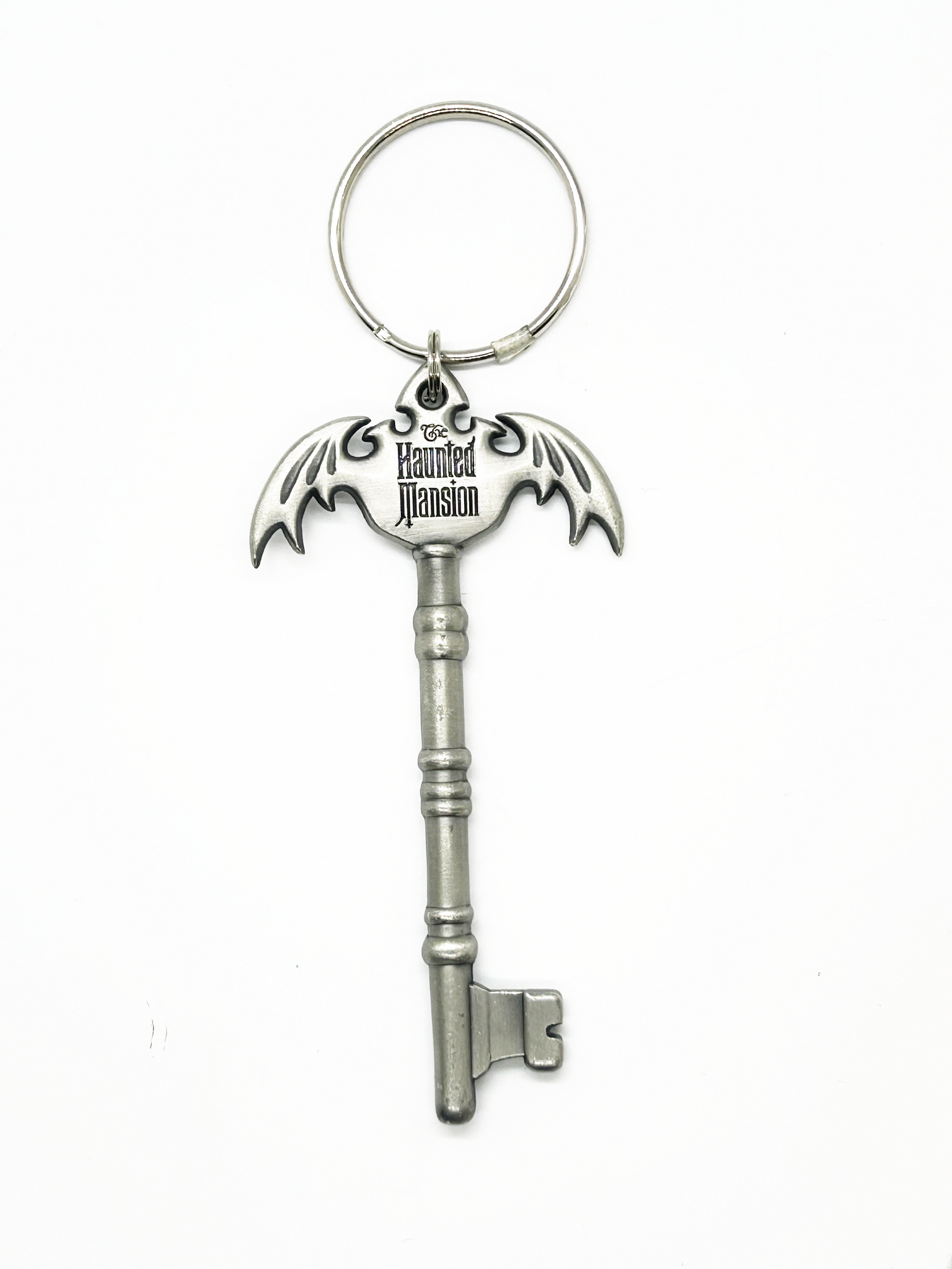 Silver key-shaped keychain with 'The Haunted Mansion' logo on a white background