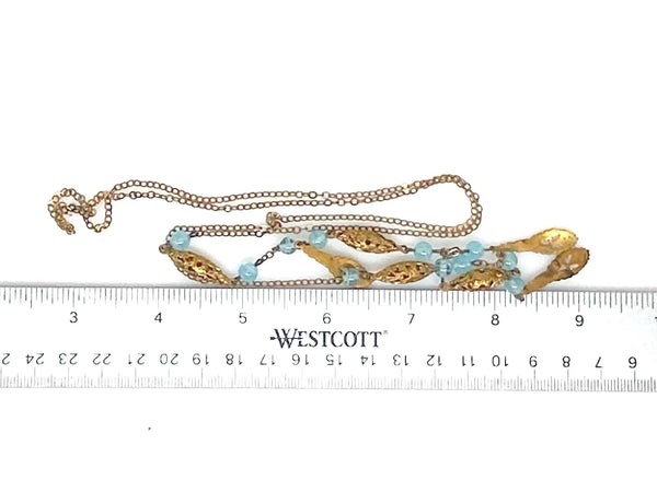 This is a beautiful antique drop necklace, made of golden filigree beads interspersed with clear blue glass accent beads, and punctuated by flat abstract filigree drops. 