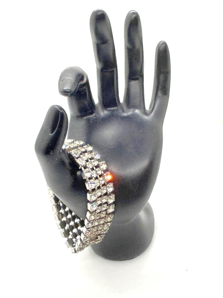 This vintage rhinestone bracelet provides an elegant touch to any ensemble. Featuring four rows of meticulously prong-set rhinestones, it measures approximately 7 inches in length and 0.75 inches in width. 