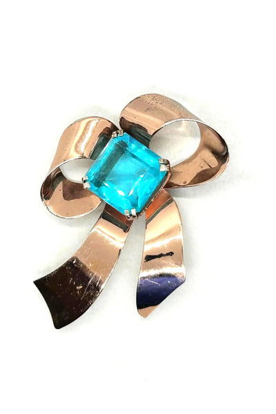 Indulge in timeless elegance with our Vintage Sterling Bow Brooch. The magnificent bow design is adorned with a stunning, clear aqua blue stone, offering a touch of luxury to any outfit. Crafted with precision, this brooch is marked sterling and measures 3 x 2 1/2”, proving to be a truly exclusive piece.