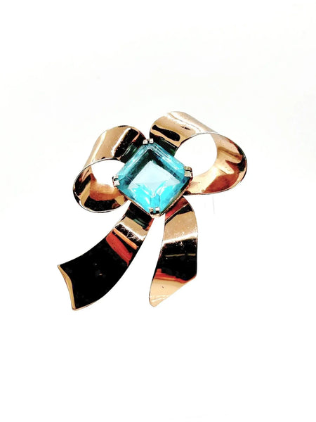 Indulge in timeless elegance with our Vintage Sterling Bow Brooch. The magnificent bow design is adorned with a stunning, clear aqua blue stone, offering a touch of luxury to any outfit. Crafted with precision, this brooch is marked sterling and measures 3 x 2 1/2”, proving to be a truly exclusive piece.