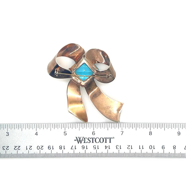 Indulge in timeless elegance with our Vintage Sterling Bow Brooch. The magnificent bow design is adorned with a stunning, clear aqua blue stone, offering a touch of luxury to any outfit. Crafted with precision, this brooch is marked sterling and measures 3 x 2 1/2”, proving to be a truly exclusive piece.