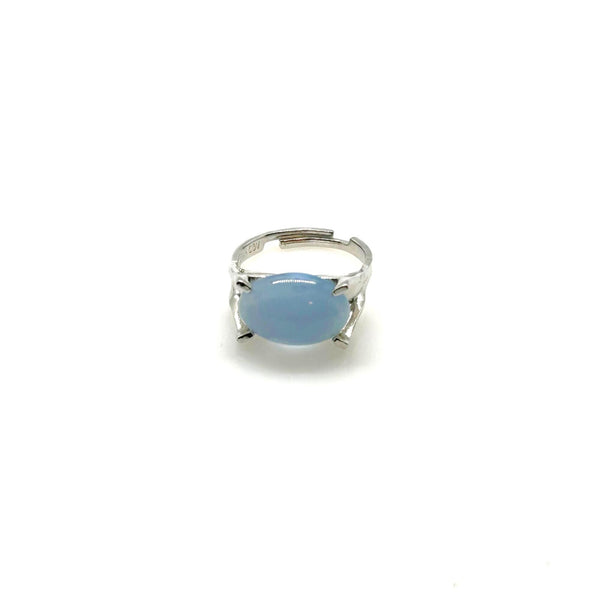 Minimalist silver statement ring with a prominent, opaque sky-blue oval stone cabochon centered on a polished silver tone adjustable band marked Sarah Cov.