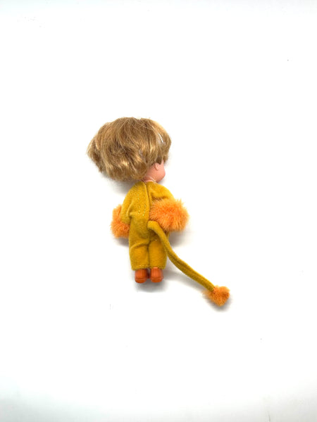 Vintage 2000 Mattel Kelly Club Lion Liana doll in a plush yellow and orange lion costume. The miniature blonde Barbie friend doll features fuzzy wrist cuffs, matching orange boots, and a long tufted tail against a solid white background