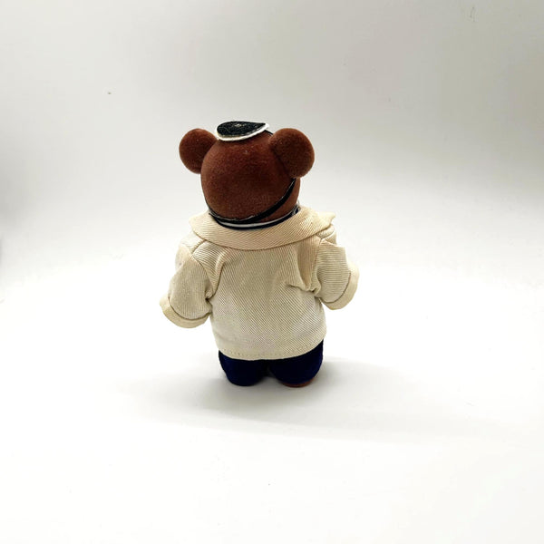 A small brown plush teddy bear dressed up as a medical doctor