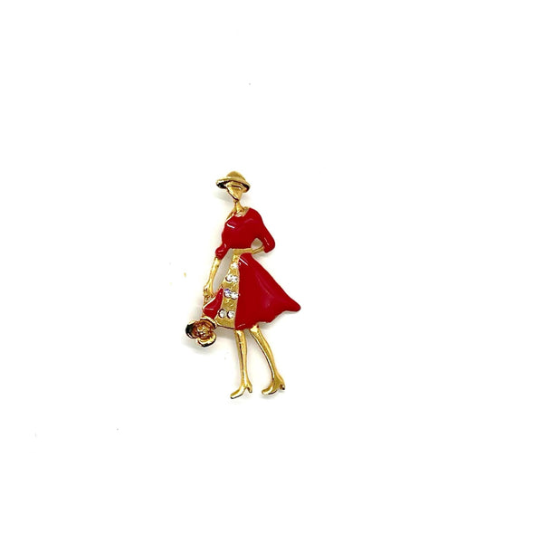 The highlighted item is a vintage enameled lady figural brooch, showing a stylish woman dressed in a vibrant red coat or dress with a wide-brimmed hat. 