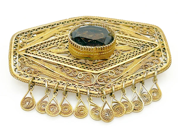 Vintage Israel Filigree Brooch/pendant with Tassels and Smokey Quartz center Stone.It has a geometric shape with tiny filigree drops at the bottom, and a large, faceted oval stone is the centerpiece. The metal is extremely intricate and detailed, both front and back.