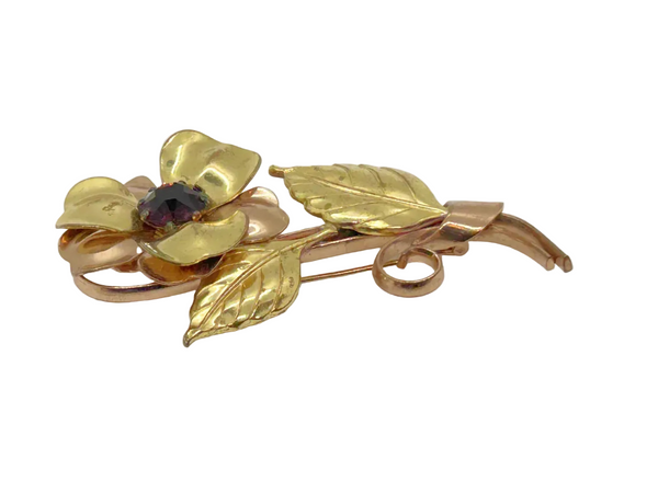 Bring a touch of vintage glamour to any outfit with this stunning, handmade flower brooch. Its beautifully crafted copper and gold petals and leaves surround a sparkling purple center, making it a striking statement piece that will surely turn heads.