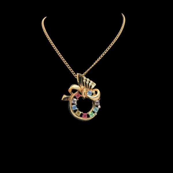This lovely necklace features a round circular pendant studded with pastel colored rhinestones and topped off with a pave set flourish. It comes with a gold tone chain. The pendant measures 1.75” and the chain measures 15” and is signed Lisner in capital letters on the fold over clasp.