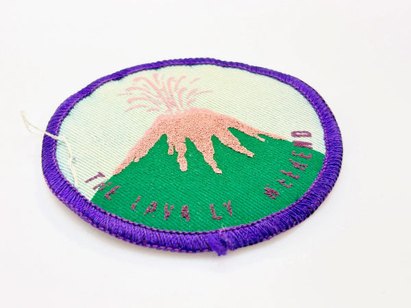 Commemorate a pivotal moment in natural history with this authentic Girl Scout Mount St. Helens patch from the early 1980s. Created in the wake of the volcano's catastrophic 1980 eruption, this Junior Girl Scout badge captures the dramatic geological event through embroidery—a volcano erupting in shades of pink against a serene blue-green sky.