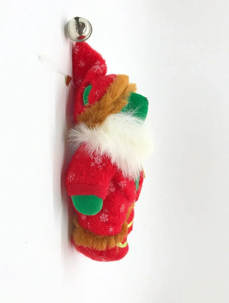 A small plush Christmas gnome ornament wearing a red outfit with green accents, a white beard, and a brown hat.