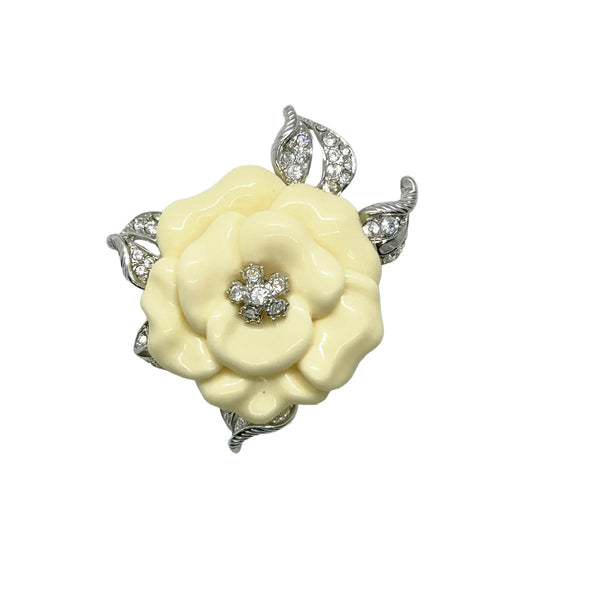 Vintage Nolan Miller Lara camellia flower brooch featuring carved cream lucite petals, a central clear rhinestone cluster, and textured silver-tone metal leaves