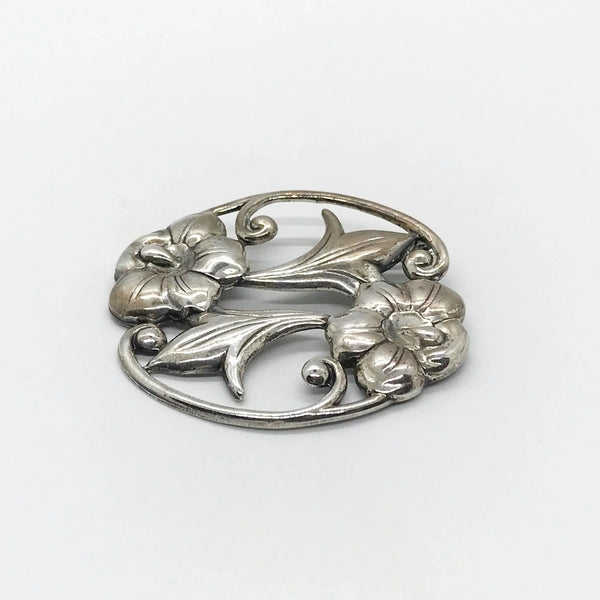 This stunning Art Nouveau floral brooch captivates with two beautiful blooms in an elegant oval shape. 