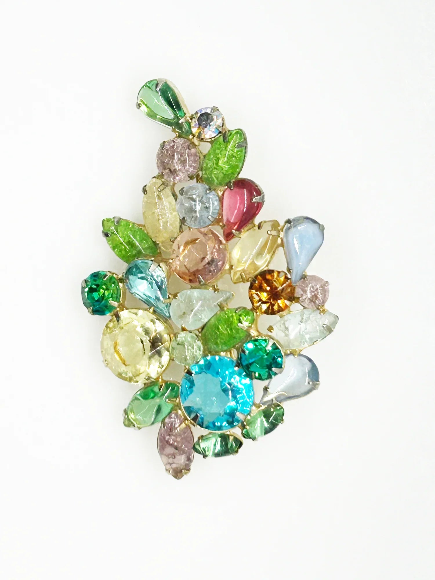 This gorgeous vintage brooch features a multicolored array of stones, including aqua, pale gold, shades of green, pink, and blue in round, marquise, and pear shapes.