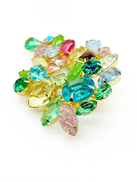 This gorgeous vintage brooch features a multicolored array of stones, including aqua, pale gold, shades of green, pink, and blue in round, marquise, and pear shapes.