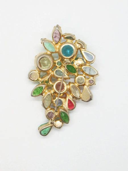 This gorgeous vintage brooch features a multicolored array of stones, including aqua, pale gold, shades of green, pink, and blue in round, marquise, and pear shapes.