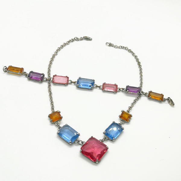 A silver-tone chain necklace with rectangular multicolor gemstones in pink, blue, purple, and orange, displayed on a clean white background.