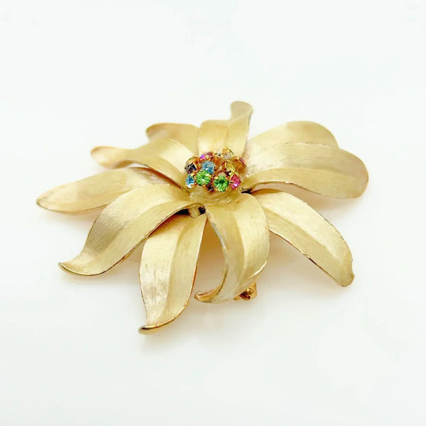 This is an elegant flower brooch which has a trembler center composed of prong set pastel rhinestones. The petals are sculpted and textured on both front and back.