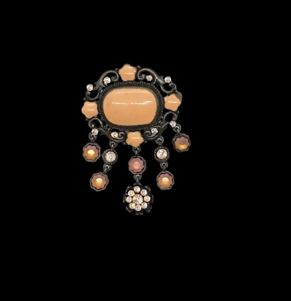 Level up your vintage jewelry collection with this stunning coral-hued brooch that captures timeless elegance. The piece showcases a luminous pale melon-orange centerstone framed by delicate star-shaped accents and peachy rhinestones that catch the light beautifully.