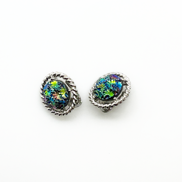 Discover the captivating allure of these authentic Sarah Coventry "Northern Lights" clip-on earrings, a stunning find from the 1960s-70s era. The dichroic glass centers showcase an extraordinary color-shifting quality that transforms from blue to green to purple to red as light dances across the surface—creating a mesmerizing effect that draws admiration from every angle.