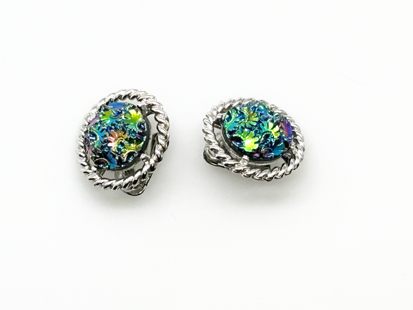 Discover the captivating allure of these authentic Sarah Coventry "Northern Lights" clip-on earrings, a stunning find from the 1960s-70s era. The dichroic glass centers showcase an extraordinary color-shifting quality that transforms from blue to green to purple to red as light dances across the surface—creating a mesmerizing effect that draws admiration from every angle.