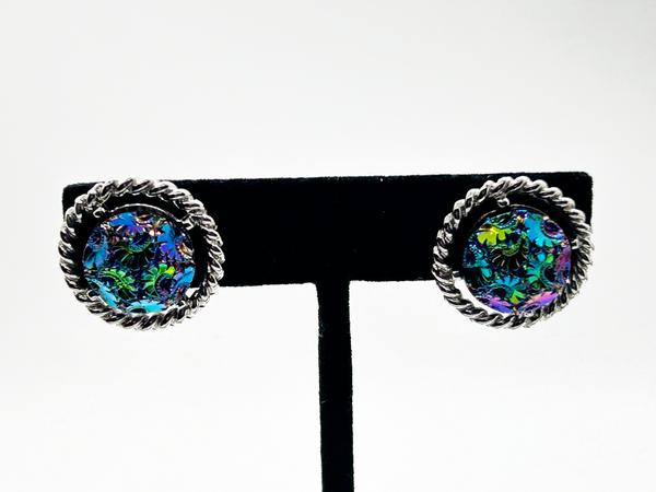 Discover the captivating allure of these authentic Sarah Coventry "Northern Lights" clip-on earrings, a stunning find from the 1960s-70s era. The dichroic glass centers showcase an extraordinary color-shifting quality that transforms from blue to green to purple to red as light dances across the surface—creating a mesmerizing effect that draws admiration from every angle.