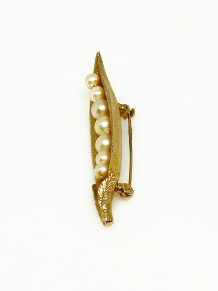 This vintage-inspired brooch features a brushed gold finish and showcases seven delicately graduated faux pearls, measuring 2.75 inches in length.
