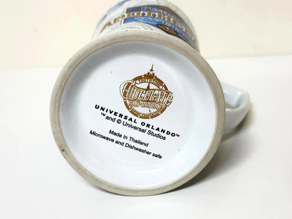 Universal Studios Toothsome Chocolate Emporium Penelope's Apothecary Sweets tall ceramic pedestal mug with blue, white, and gold geometric pattern on a solid white background.