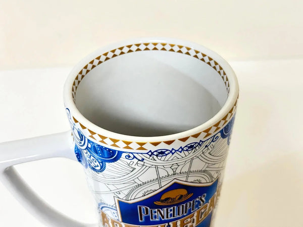 Universal Studios Toothsome Chocolate Emporium Penelope's Apothecary Sweets tall ceramic pedestal mug with blue, white, and gold geometric pattern on a solid white background.