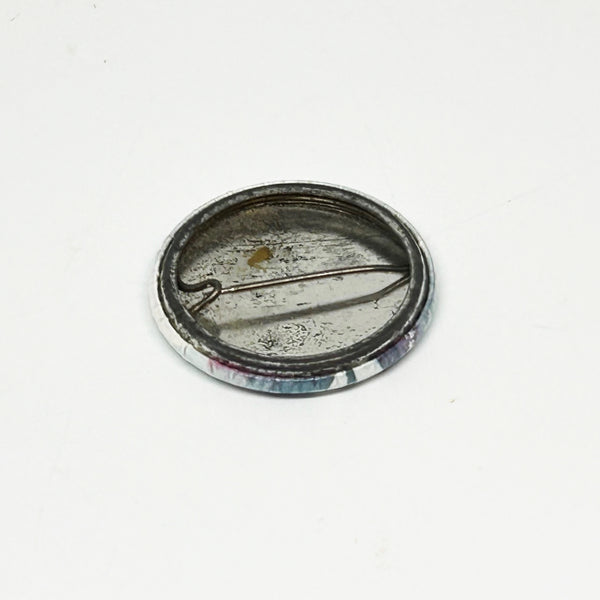 Reverse side of a vintage 1984 Prince Purple Rain pinback button badge, showing the tarnished metal back, springless wire pin mechanism, and open catch cradle on a clean white background
