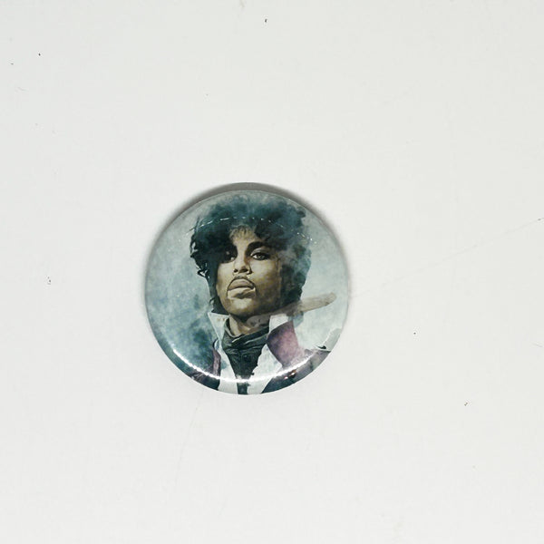 A vintage 1984 Prince pinback button badge featuring a painted portrait of Prince Rogers Nelson during the Purple Rain era