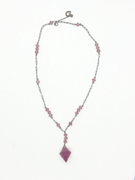 This stunning vintage crystal necklace showcases clusters of deep purple bicone beads, interspersed with sleek paper clip chains. It culminates in a magnificent faceted diamond-shaped stone. Measuring 16.5 inches in length, with a drop of 1.5 inches from the center, this piece exudes elegance and sophistication.