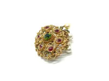 Product photo of a vintage antique-gold filigree pin. The central oval frame holds bright green and red glass gems. Six small dangling charms hang from the bottom, including five creamy white pearls and one round green rhinestone.