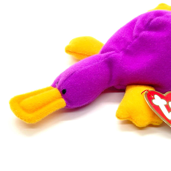 Purple and yellow plush toy with a visible brand tag on a white background