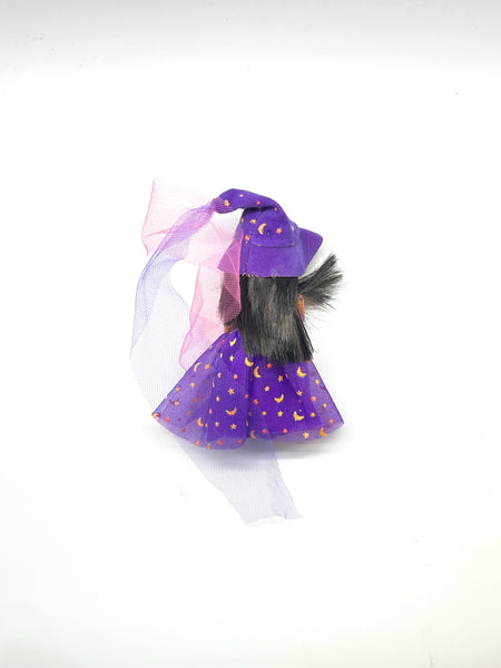 A vintage 2003 Mattel Barbie Kelly Club Halloween Party Deidre as a Witch mini doll. The doll features brown hair and is wearing a purple dress and matching pointed witch hat decorated with gold metallic stars and crescent moons, accented by a purple mesh veil. Isolated on a solid white background