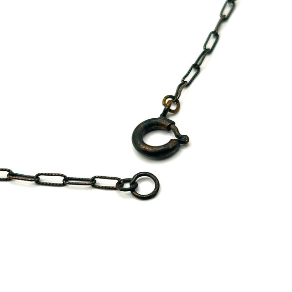 A vintage necklace featuring clusters of deep purple bicone crystal beads on a dark-toned paperclip chain, culminating in a large, heavily faceted diamond-shaped purple crystal drop pendant