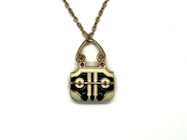 Take your your accessory game to the next level with this enchanting vintage purse necklace, a miniature work of art that celebrates timeless style. The handbag-shaped pendant showcases exquisite black and cream enamel detailing with bold geometric striping, evoking the sophisticated aesthetic of luxury designer bags from the 1980s-1990s era.