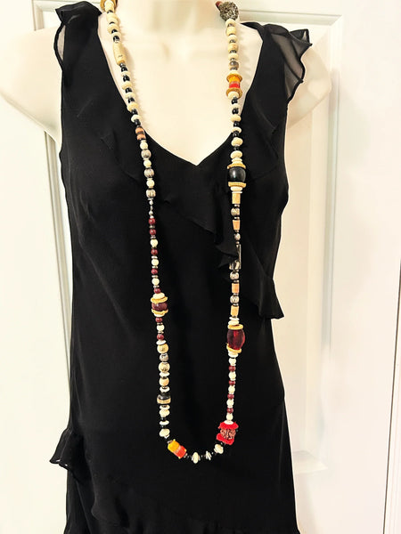 This captivating necklace is a true statement piece, boasting a unique blend of beads in an array of shapes and sizes. The earthy, nature-inspired hues create a stunning visual, with warm tones of red, black, and cream that beautifully coordinate with any fall ensemble. At nearly 60 inches in length, this adaptable infinity necklace is designed without a clasp, providing endless styling possibilities.