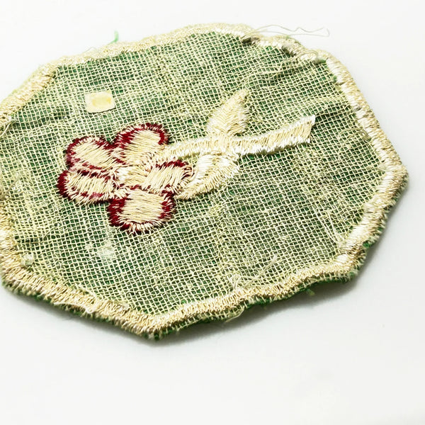 This is a vintage Girl Scout troop crest patch, featuring a red flower design with a white center and stem on a green octagonal background. This specific design has been retired. It depicts either a Scarlet Pimpernel or a Cardinal Flower, with the specific name depending on the era 