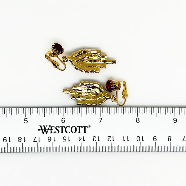 Bright red sparkling round rhinestones glitter in a gold tone setting. They give Art Deco vibes while being easy to wear and fun. They each measures 2" long and are in near mint condition, with hinge backs.