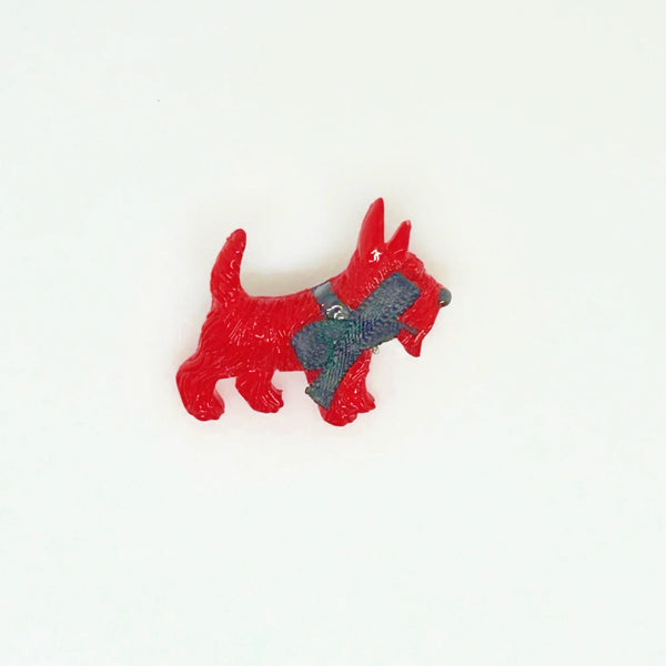 Adopt this captivating and unusual Scottie Dog Brooch, crafted in a bold red hue with a lavish black ribbon bow adorning its neck. Measuring 1.25" in width, it is in impeccable condition. His black collar and nose complete the look. 