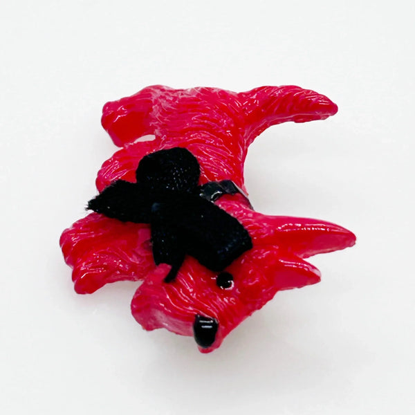 Adopt this captivating and unusual Scottie Dog Brooch, crafted in a bold red hue with a lavish black ribbon bow adorning its neck. Measuring 1.25" in width, it is in impeccable condition. His black collar and nose complete the look. 