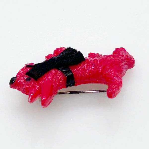 Adopt this captivating and unusual Scottie Dog Brooch, crafted in a bold red hue with a lavish black ribbon bow adorning its neck. Measuring 1.25" in width, it is in impeccable condition. His black collar and nose complete the look. 