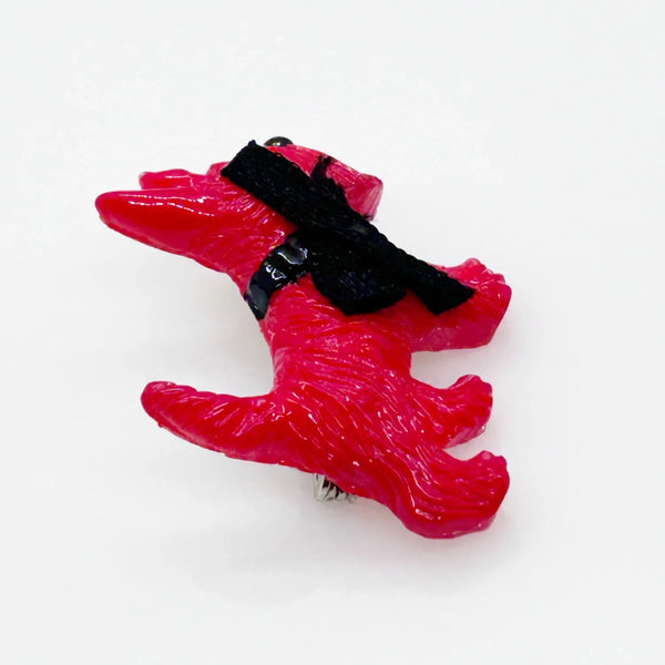 Adopt this captivating and unusual Scottie Dog Brooch, crafted in a bold red hue with a lavish black ribbon bow adorning its neck. Measuring 1.25" in width, it is in impeccable condition. His black collar and nose complete the look. 