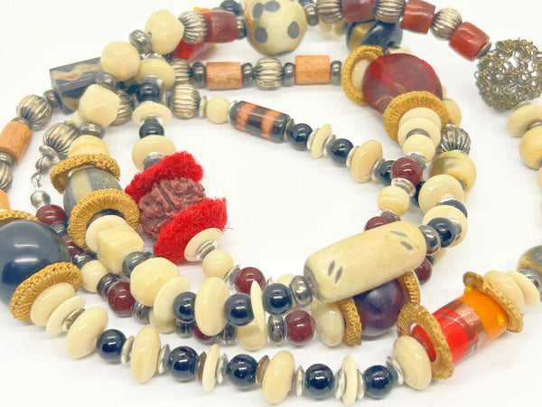 This captivating necklace is a true statement piece, boasting a unique blend of beads in an array of shapes and sizes. The earthy, nature-inspired hues create a stunning visual, with warm tones of red, black, and cream that beautifully coordinate with any fall ensemble. At nearly 60 inches in length, this adaptable infinity necklace is designed without a clasp, providing endless styling possibilities.