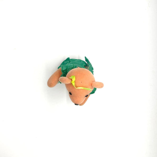 A small plush teddy bear ornament wearing a green floral dress and a yellow bow, standing against a plain white background.